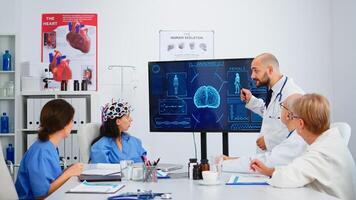 Neurologist showing new inovation to colleagues discussing brain functions using high tech in medical boardroom. Medic studying diagnosis of patients working in hospital conference room photo