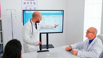 Expert doctor presenting to his team the list of sick patients deciding together their priority. Team of doctors discussing diagnosis about treatment of patients working in hospital boardroom photo