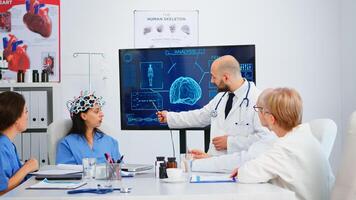 Team of doctors analysing brain functions using high tech in medical conference room, assistant testing new innovation. Medic studying diagnosis for treatment of patients working in hospital boardroom photo
