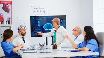 Senior woman neurologist analysing brain functions using high tech in medical conference room, doctor testing new innovation. Medic studying diagnosis for treatment of patients working in boardroom photo