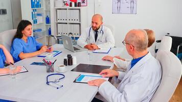 Academic meeting of expert doctors discussing about symptoms of disease working in hospital conference room. Clinic expert therapist talking with colleagues about treatment of patients photo