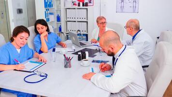 Medical practioner checking list with patients on clipboard talking with doctor during boardroom meeting. Clinic expert therapist discussing with colleagues about disease, medicine professional. photo