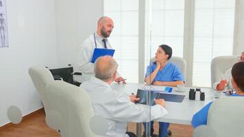 Medical practitioner presenting diagnosis to colleagues holding clipboard during briefing with coworkers. Clinic expert therapist talking with colleagues about disease, medicine professional photo