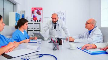 Doctor having professional discussion with medical staff in hospital meeting room. Clinic expert therapist talking with colleagues about disease, medicine professional, analysing diagnosis of patients photo