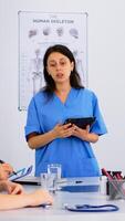 Medical people meeting and planning with shareholders in hospital office sitting at desk. Doctors and nurses brainstorm ideas together, physicians diagnosis and presentation data using tablet photo