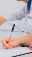 Close up of nurse writing on clipboard while coworkers discussing in background analysing patients radiography. Profesional teamworkers having medical meeting, brainstorming in hospital office. photo