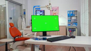 Computer with chroma key pc desktop placed in front of camera in empty equipped stomatological room. Stomatology clinic with nobody in it prepared for patient using green screen, mockup display photo