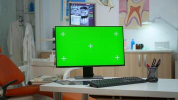 Computer with mockup display placed in front of camera in empty equipped stomatological room. Stomatology clinic with nobody in it prepared for patient using green screen, chroma key pc desktop photo