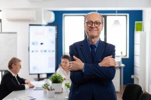 Portrait of succesful senior entrrepeneur in conference room smiling at camera with arms crossed. Manager working in professional start up financial business, modern company workplace ready for meeting. photo