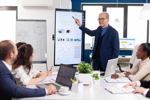 Experienced project leader analysing financial presentation during business conference in brainstorming room using digital devices. Multiethnical businesspeople working in professional startup financial office during conference meeting. photo