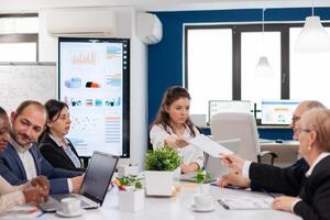 Woman company leader talking at diverse group board meeting, multiethnic team. Businesswoman discussing ideas with colleagues about financial strategy for new start up company. photo