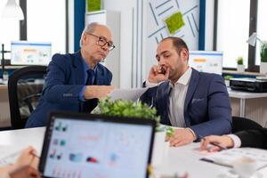 Financial entrepreneurs analysing discussing documents in corporate briefing room. Businessman discussing ideas with colleagues about financial strategy for new start up company. photo