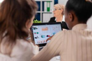 African american entrepreneur and coworkers analysing charts in conference room. Businesswoman discussing ideas with colleagues about financial strategy for new start up company working in brainstorming office. photo