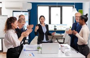 Happy diverse coworkers applauding after successful presentation. Multiethnical partners coworkers celebrate successful teamwork result at company briefing photo