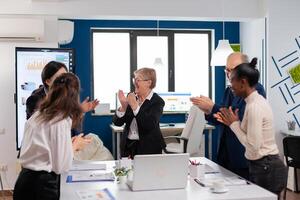 Happy excited diverse team of financial team in conference room after successful strategy. Multiethnical partners coworkers celebrate successful teamwork result at company briefing photo