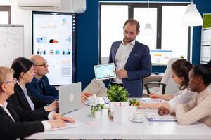 Company leadership explaining briefing project in conference room to team. Project leader discussing with teamworkers in broadroom, analysing charts, graphs, financial evolution of company. photo