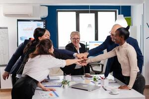 Happy creative multiethnic business team celebrating successful project. Diverse colleagues with new opportunity enjoing victory meeting in broadroom office. photo