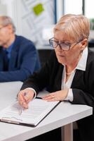 Busiess partners discussing new project for company evolution, senior manager woman checking tasks. Executive director meeting shareholders in start up office, making satisfactorily agreement. photo