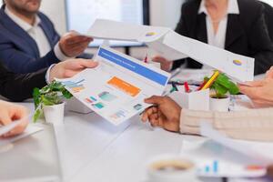 Close up of diverse startup company colleagues meeting in professional workplace, brifing and sharing ideas over financial strategy. Colleagues working in office at conference table in startup management company. photo
