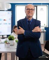 Portrait of succesful senior entrrepeneur in conference room smiling at camera with arms crossed. Manager working in professional start up financial business, modern company workplace ready for meeting. photo