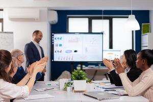 Succesful business man presenting the good evolution of company using digital device. Diverse multiethnic colleagues with new opportunity enjoing victory meeting in broadroom office. photo