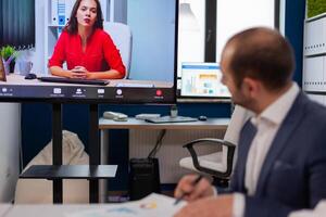 Executive manager discussing with remote colleagues on call sitting in business office Business people talking to webcam, do online conference participate internet brainstorming, distance office discussion. photo