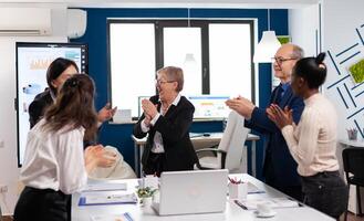 Happy excited diverse team of financial team in conference room after successful strategy. Multiethnical partners coworkers celebrate successful teamwork result at company briefing photo