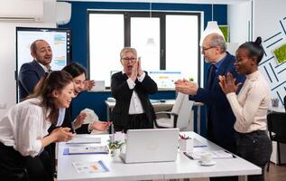 Diverse executive business team clapping in conference room during training. Multiethnical partners coworkers celebrate successful teamwork result at company briefing photo