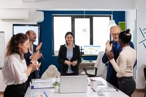Happy overjoyed financial startup team standing clapping a in conference briefing. Multiethnical partners coworkers celebrate successful teamwork result at company briefing photo