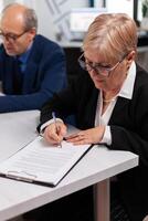 Woman reading financial documents in conference room before signing it. Executive director meeting shareholders in start up office, making satisfactorily agreement. photo