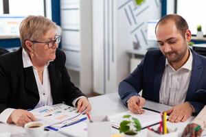 Young businessman reading documents, sign its and consultant greeting international client with handshake after planning partnership deal. Executive director meeting shareholders in start up office photo