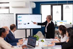 Senior woman company leader brainstorming in conference room Corporate staff discussing new business application with colleagues looking at screen photo