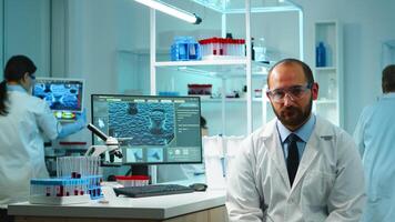 Portrait of exhausted chemist looking at camera in modern equipped lab late at night. Team of biochemists examining virus evolution using high tech and chemistry tool for research, vaccine development photo