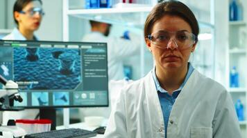 Close up of scientist nurse looking tired at camera sitting in modern equipped laboratory late at night. Team of specialists examining virus evolution using high tech for research, vaccine development photo