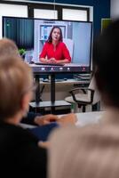 Diverse business team having videomeeting discussing online with remotely executive manager in business office. Business people talking to webcam, do online conference participate internet brainstorming, distance office discussion. photo