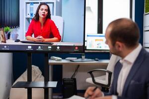 Executive manager discussing with remote colleagues on call sitting in business office Business people talking to webcam, do online conference participate internet brainstorming, distance office discussion. photo