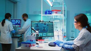Chemist nurse sitting in scientific equipped lab examining virus evolution using high tech researching treatment against covid19 virus, typing results of tests on computer working overtime. photo