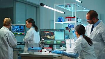 Research scientists working on pc with medical equipment analyzing blood and genetic material samples with special program in modern equipped laboratory. Multiethnic team examining virus evolution photo