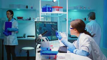 Woman biochemist checking manifestations of virus working on computer in equipped lab late at night. Team of doctors examining vaccine evolution using high tech researching diagnosis against covid19 photo