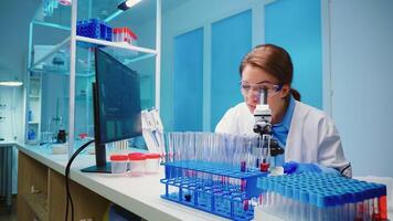 Team of scientist checking virus development using microscope analysing results at night in modern equipped lab. Group of chemists examining vaccine evolution using high tech for research. photo