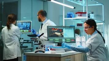 Scientist team checking virus development using high tech writing analysis results on computer in modern equipped lab at night. Doctors examining vaccine evolution with special tools for research. photo