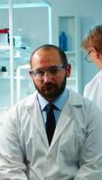 Portrait of exhausted chemist looking at camera in modern equipped lab late at night. Team of biochemists examining virus evolution using high tech and chemistry tool for research, vaccine development photo