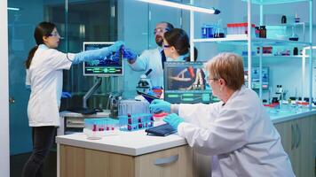 Nurse holding tablet computer with scientific informations while chemist using microscope with chemical test tube near, in lab background at night. Medical science research and development concept photo