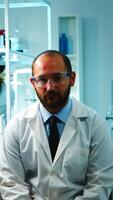 cansado médico mirando agotado a cámara en moderno equipado laboratorio tarde a noche. médico químico equipo examinando virus evolución utilizando alto tecnología y química herramientas para investigación, vacuna desarrollo. foto
