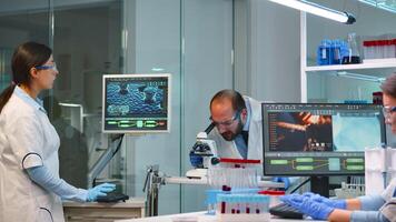 Man research scientist looking at samples under microscope while nurse writes informations on pc in modern equipped laboratory. Doctors working with various bacteria, tissue and blood tests photo