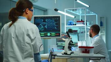 Team of medical research scientists conducting vaccine development with help of high tech, test tubes, micropipette and writing down analysis results on computer in modern equipped laboratory at night photo