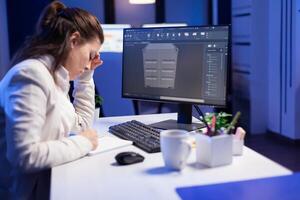Focused architect working in 3D software developing prototype container design sitting at desk in business office. Technician engineer creating and studying project prototype, analysing scale model photo