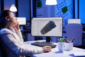 Project designer engineer analizing concept idea of 3D model of the plant yawning working overtime. Industrial woman worker studying turbine idea on pc showing cad software on device display photo