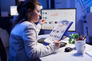 Focused businesswoman checking graphics from nootebook, working at financial strategy from office worker. Busy manager using modern technology network wireless searching business solution photo