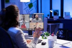 Manager during online conference with corporate team after midnight using pc in start up business office. Videoconference internet meeting with technology network wireless discussing on call late at night photo